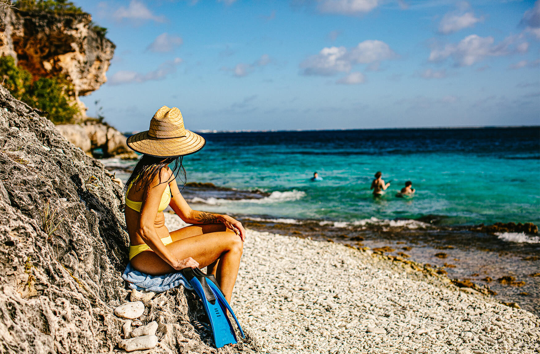 Woman sitting on rocks next to the beach